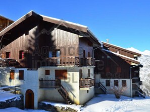 Un edificio de estilo chalé con fachada de madera, un balcón y una escalera que conduce a la entrada.