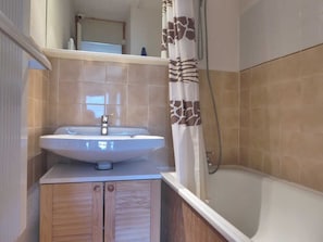 A bathroom with a sink, mirror, and shower.