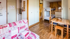 A compact room with a bunk bed, a small kitchenette, and a sofa with a patterned cover. - Divisible studio near slopes, 4 pers., parking, nice view (Bellentre)