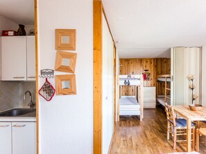 A compact kitchen with white cabinets, a wooden dining table, and a bunk bed in the background. - Divisible studio near slopes, 4 pers., parking, nice view (Bellentre)