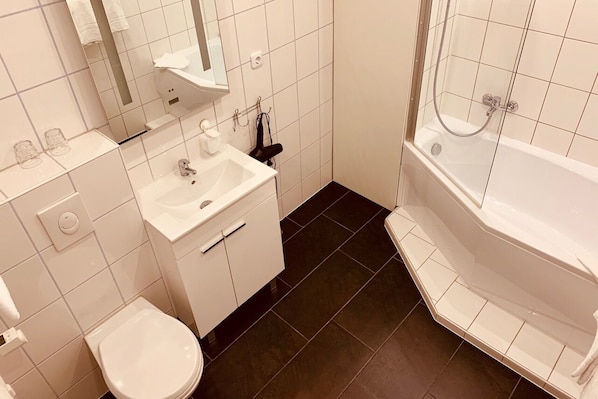 Un baño moderno con lavamanos, espejo y retrete blancos.