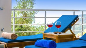 A sunlit room with a blue bed, a wooden table with two glasses of red wine, and a towel. - Villa Spring - Hill Villas Kalkan (Kas)