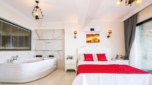 A modern bedroom with a curved bathtub, a large bed with red bedding, and a cityscape painting on the wall. - Villa Spring - Hill Villas Kalkan (Kas)