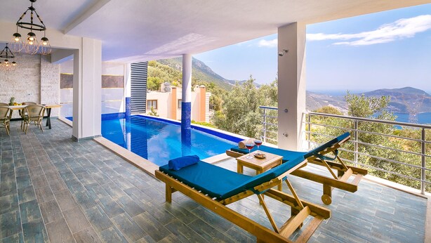 A modern indoor pool area with a view of mountains and a dining setup. - Villa Spring - Hill Villas Kalkan (Kas)
