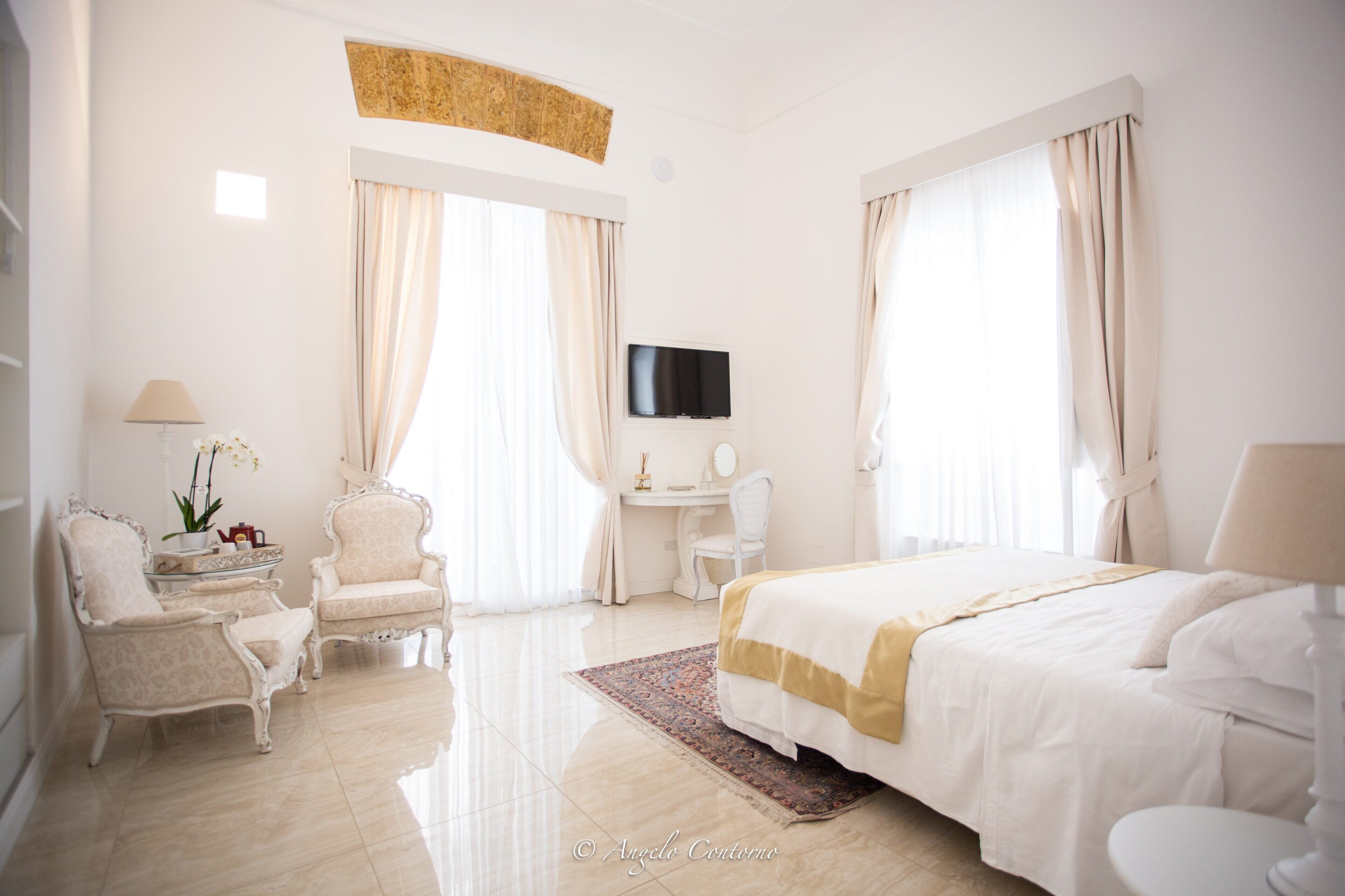 Habitació d'hotel amb un llit gran, una taula de treball, una cadira i una televisió.