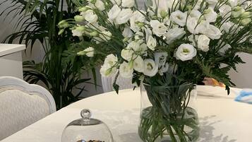 A table with a white tablecloth, a vase of white flowers, and two glass cloche-covered dessert plates.