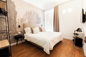 A hotel room with a bed, a desk with a phone, a TV, and a wall with a historical mural. - Palazzo del Poeta (Palermo)