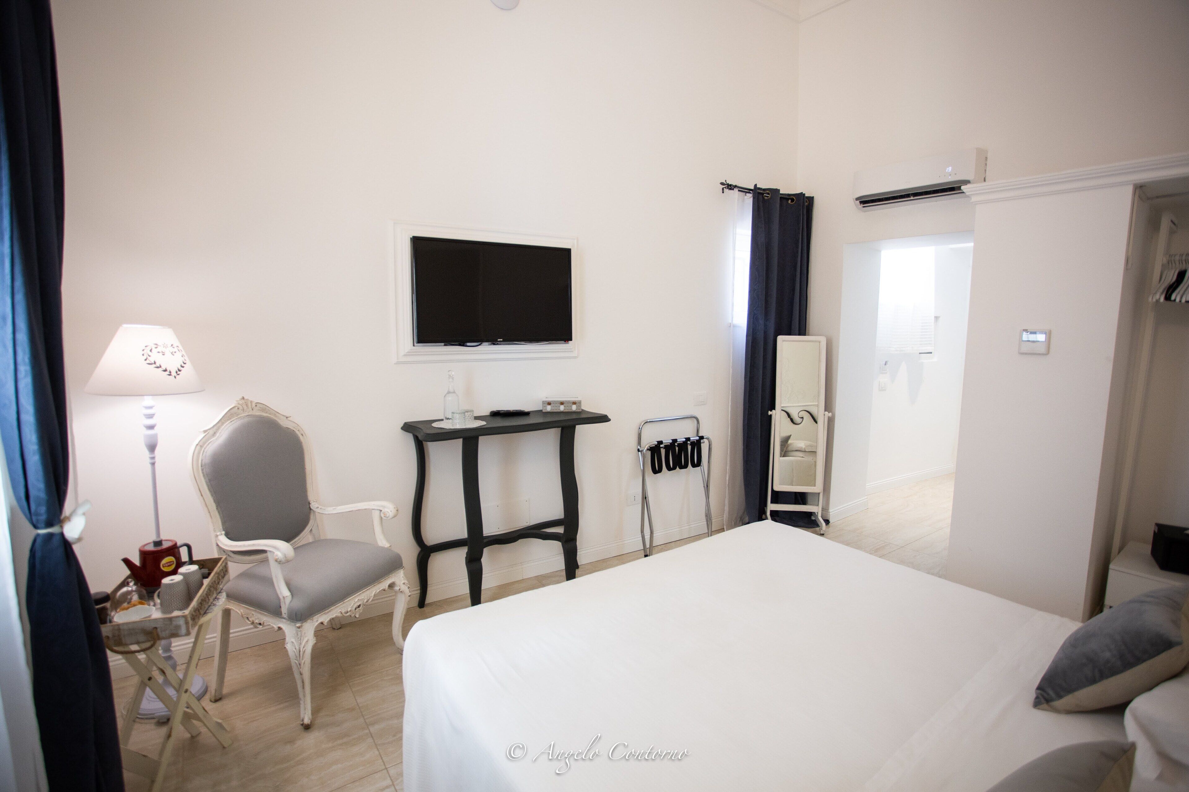 A hotel room with a bed, a chair, a small table, a TV, and a wardrobe.