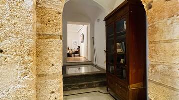 Un arco de piedra que conduce a una escalera con un armario de madera y una escultura blanca.