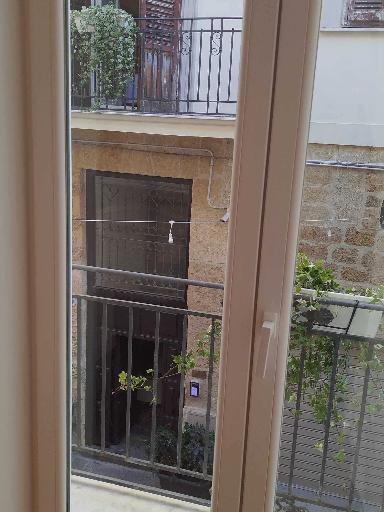 A view of a balcony with a metal railing, a stone wall, and a door with a metal gate.