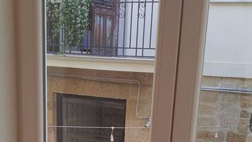 A view of a balcony with a metal railing, a stone wall, and a door with a metal gate.