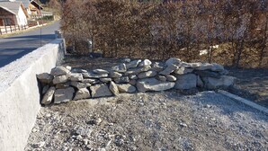 Une zone recouverte de gravier, avec un muret en pierre et un bord en béton.