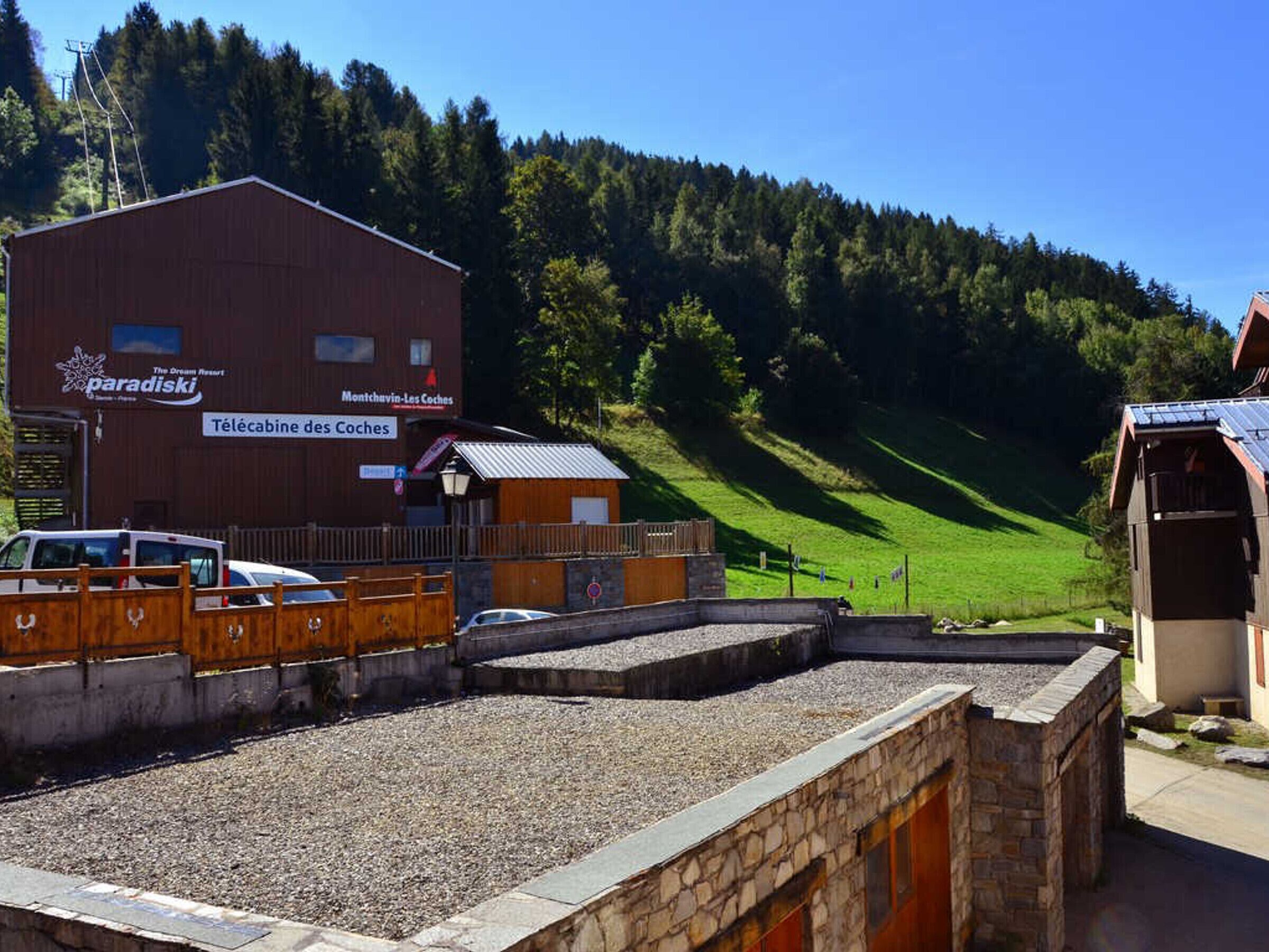 A rustic building with a sign for 'paradiski' and 'Télécabine des Coches'.