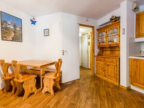 A dining area with a wooden table and chairs, a kitchen with wooden cabinets, and a framed picture on the wall.