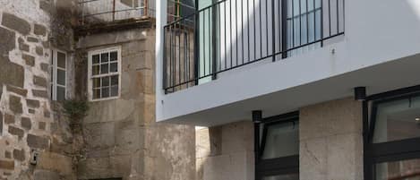 Una calle estrecha con un edificio de piedra a un lado y un edificio moderno con balcones al otro.