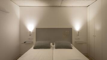 A bedroom with a double bed, two bedside tables, a wardrobe, and a headboard with a crest.