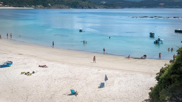 A beach with clear water, boats, and people. - Hotel SempreFisterra (Fisterra)