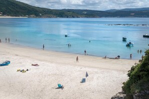 A beach with clear water, boats, and people. - Hotel SempreFisterra (Fisterra)