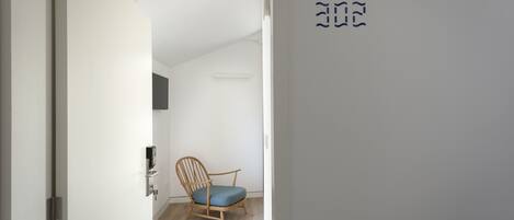 A room with a wooden chair, a door, and a wall with a symbol.