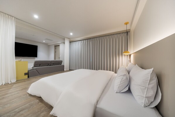 Une chambre d’hôtel moderne équipée d’un grand lit, d’un canapé, d’une télévision et d’un bureau.