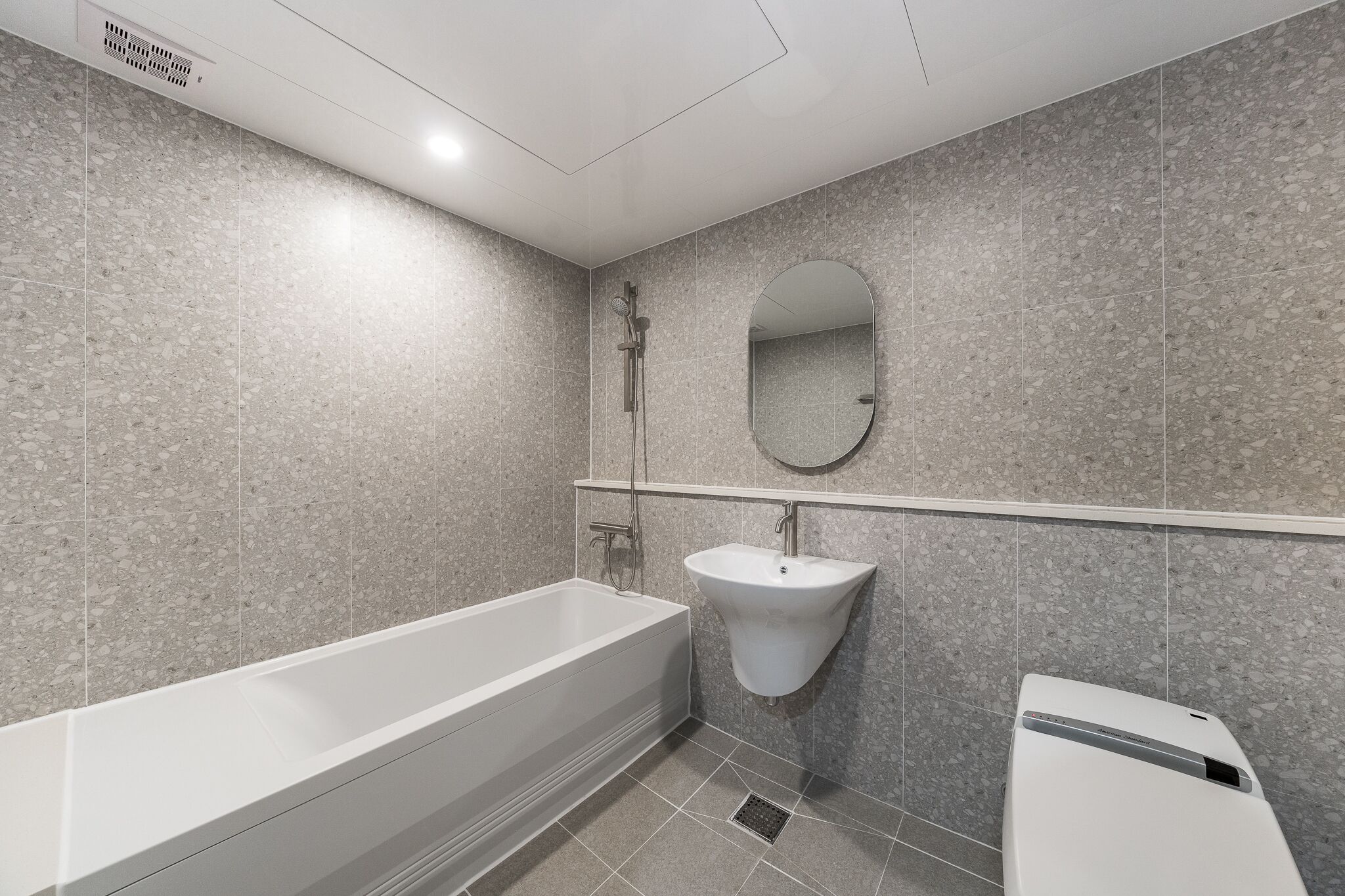 A modern bathroom with a freestanding bathtub, a wall-mounted sink, and a mirror.