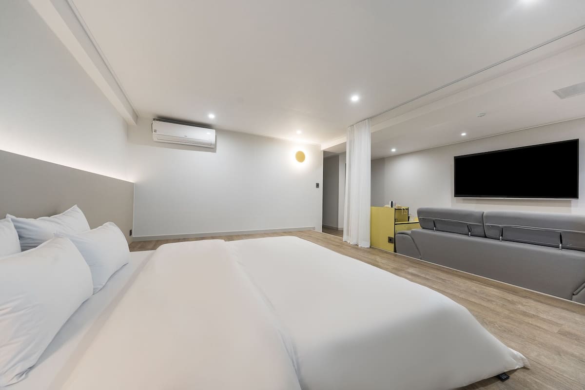 A modern hotel room with a large bed, a flat-screen TV, and a seating area.