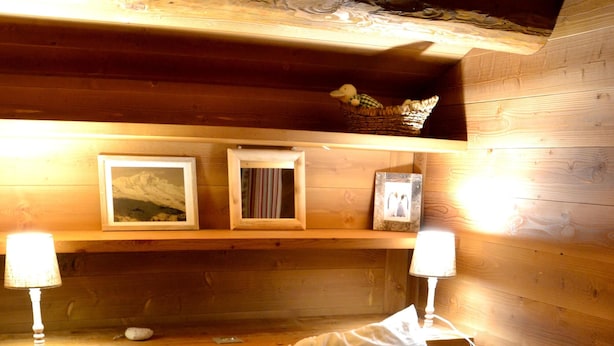 A cozy wooden cabin room with a bed featuring a white deer pillow, a framed picture of a mountain, and a basket on the shelf. - Les Eterlous - Very beautiful Chalet 200m from the slopes of La Plagne - 12-15 pers. (Aime-La-Plagne)