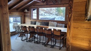 A wooden cabin interior with a large dining table, six chairs, and a window overlooking a snowy landscape. - Les Eterlous - Very beautiful Chalet 200m from the slopes of La Plagne - 12-15 pers. (Aime-La-Plagne)