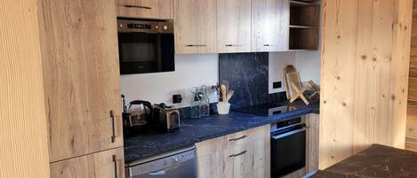 A modern kitchen with wooden cabinets, a built-in oven, a dishwasher, and a marble countertop.