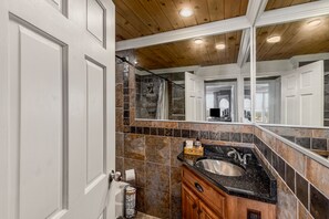 A bathroom with a wooden ceiling, a large mirror, a sink with a black countertop, and tiled walls. - The VFT Crown Suite-Downtown Atlanta Location (Atlanta)