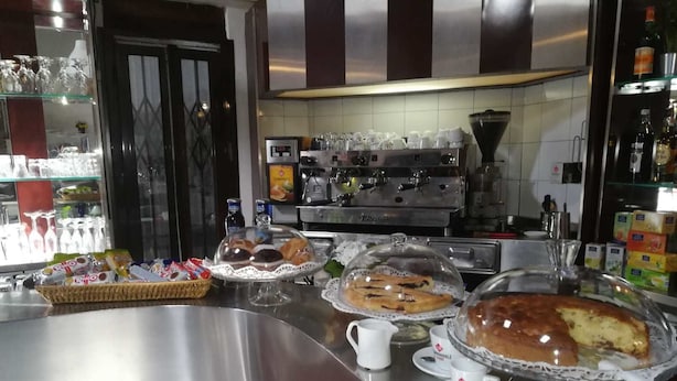 A buffet area with various food items, a coffee machine, and a refrigerator in the background. - Smeraldo Camping Village (Bracciano)