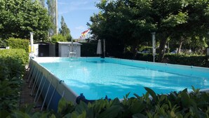 A rectangular swimming pool with a clear blue water surface, surrounded by greenery and a small structure with a flag. - Smeraldo Camping Village (Bracciano)