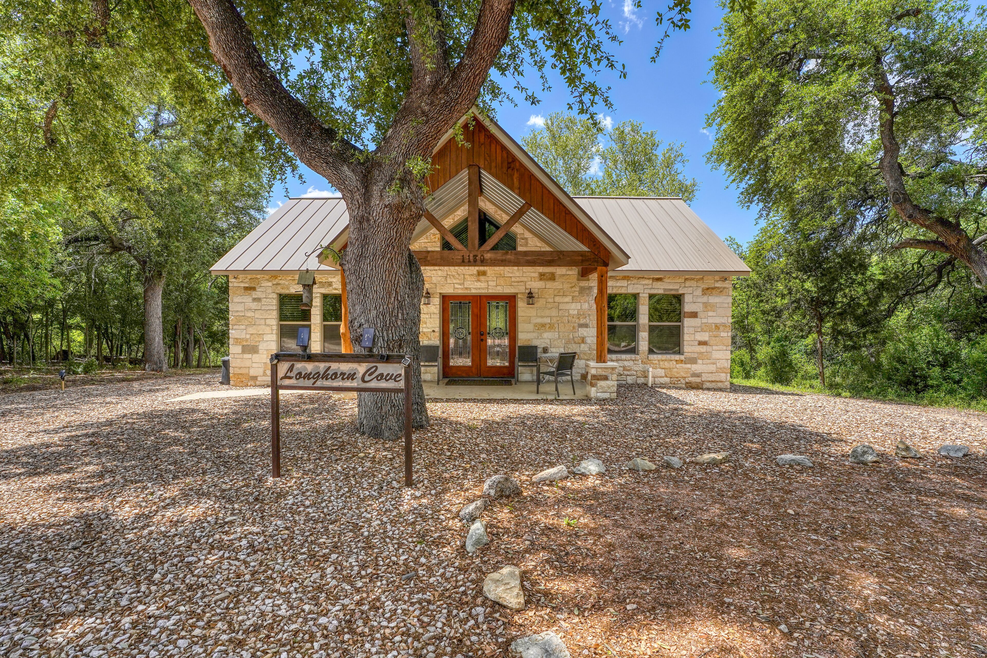 A stone building with a wooden facade, a large tree in front, and a sign reading "Longhorn Cove".
