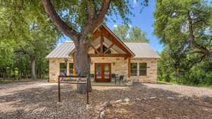 Un edificio de piedra con fachada de madera, un gran árbol en frente y un letrero que dice 'Longhorn Cove'.