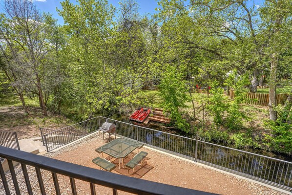 A patio with a table and chairs, surrounded by a fence and trees.