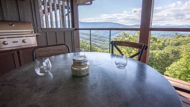 A dining table with a view of a mountainous landscape through large windows.