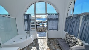 A bathroom with a bathtub, a shower, and a glass-enclosed window. - Thirassia Paradise Suites (Therasia)