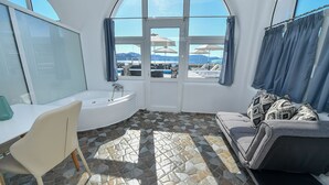 A bathroom with a bathtub, a sink, and a window overlooking a pool area. - Thirassia Paradise Suites (Therasia)
