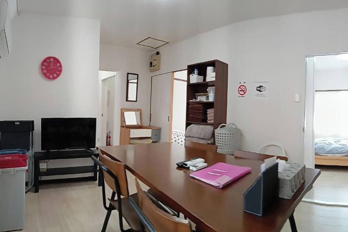 A room with a wooden desk, a chair, a bed, a wardrobe, a mirror, and a clock.