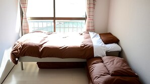 Un dormitorio con cama, un banco y una ventana con cortinas.
