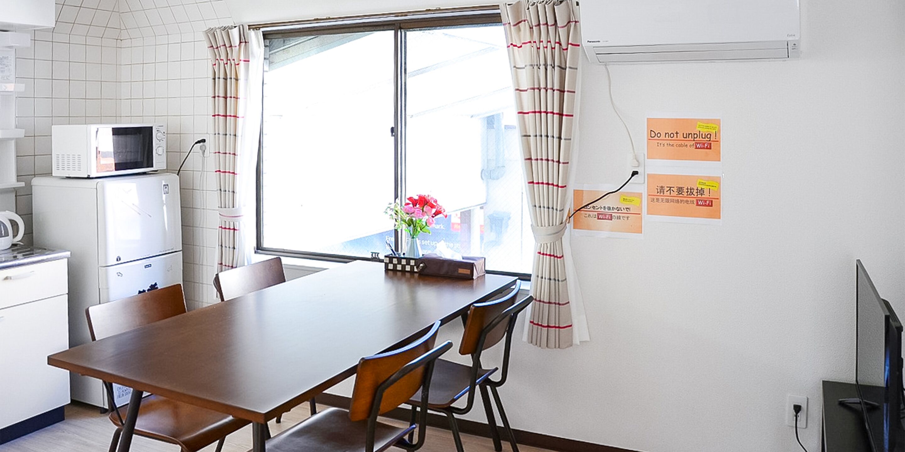 A compact kitchen with a microwave, refrigerator, and dining area with a table and chairs.