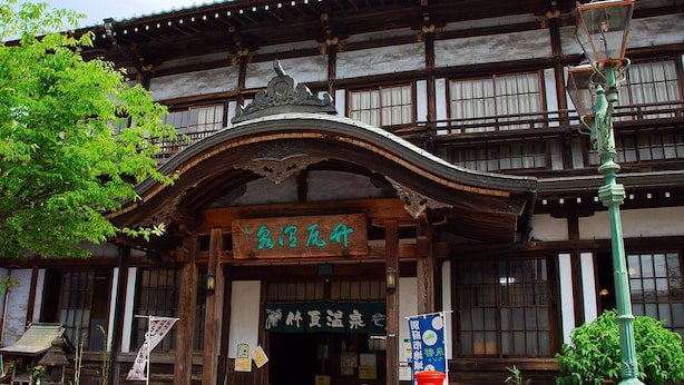 Un edificio japonés tradicional con fachada de madera, una entrada curva y un letrero con caracteres japoneses.
