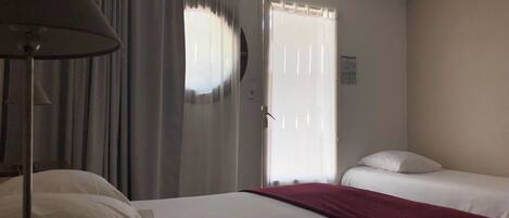 Habitación de hotel con cama, escritorio, lámpara y ventana con cortinas.