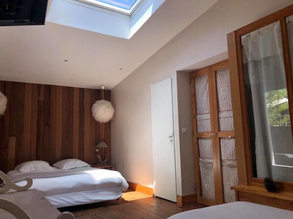 Un dormitorio con dos camas, paredes de paneles de madera, un tragaluz y un ventanal grande con cortinas.