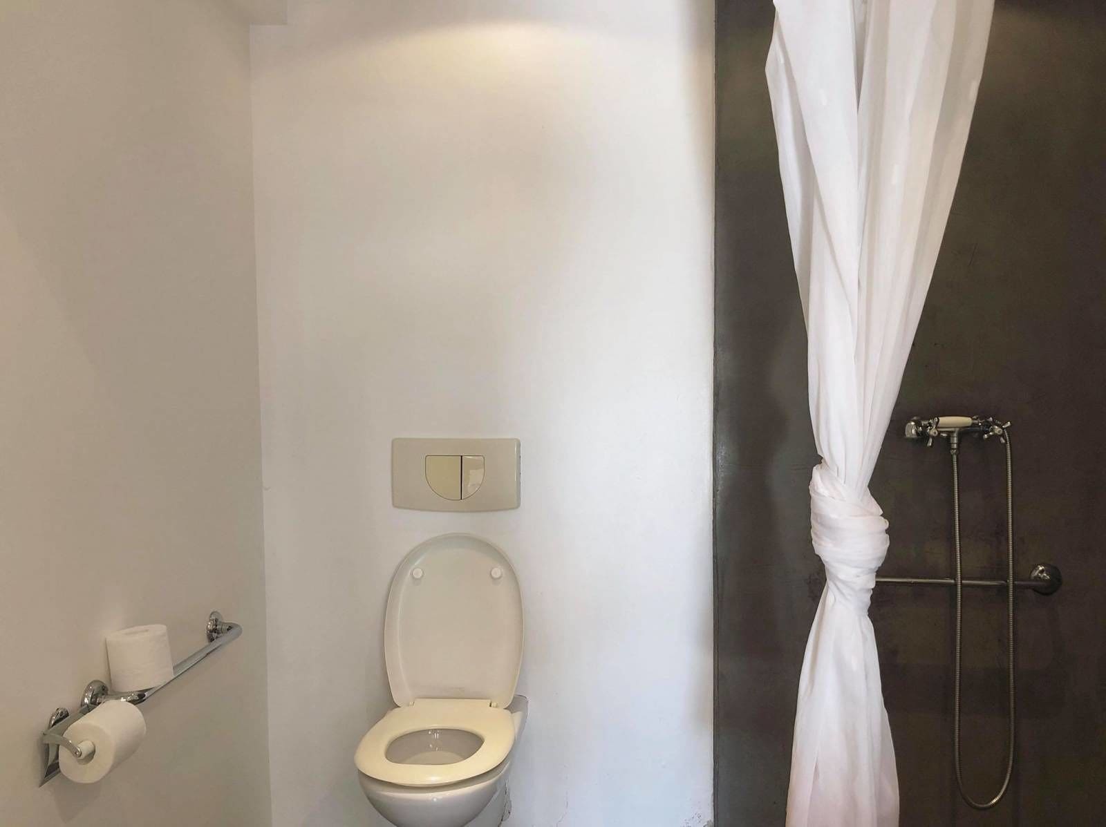 A bathroom with a toilet, a towel rack, and a shower curtain.