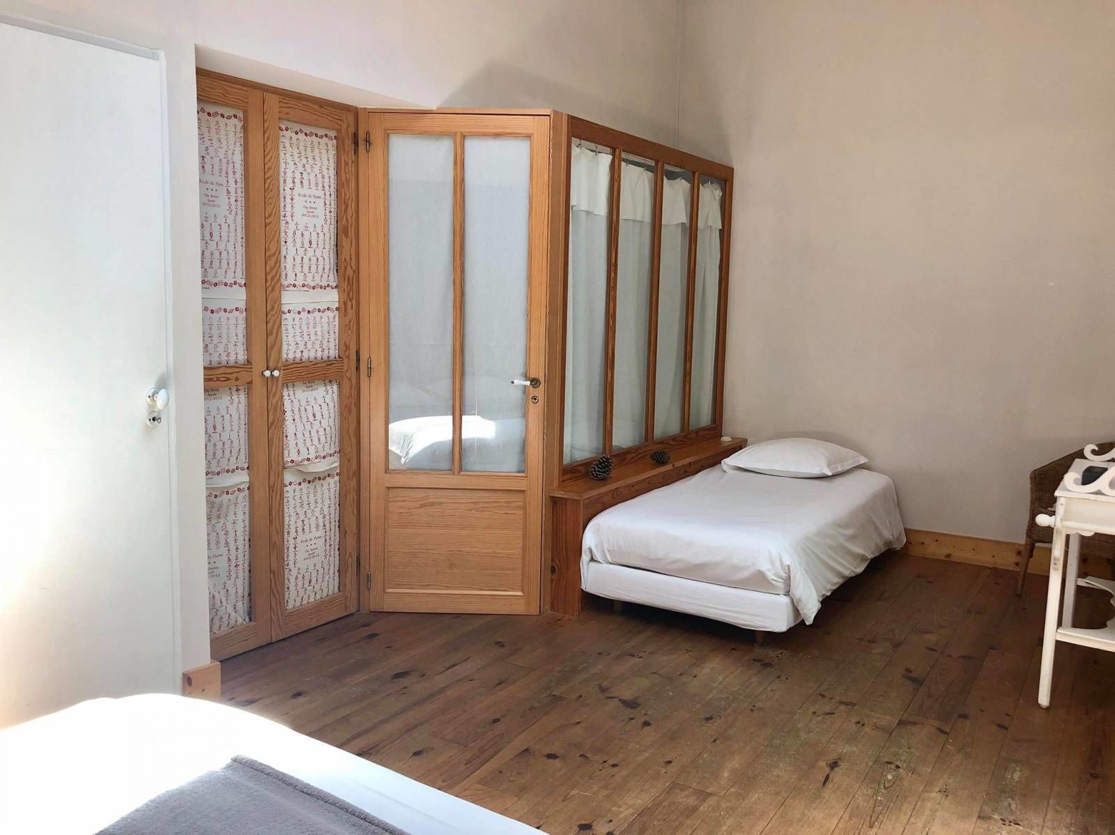 Un dormitorio con un armario de madera, una cama y una pequeña mesa.