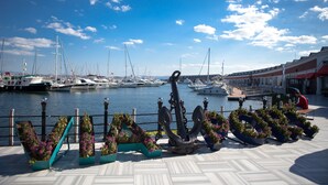 A marina with boats docked, a large anchor sculpture, and potted plants with flowers. - Tuzla Garden Hotel & Spa (Tuzla)