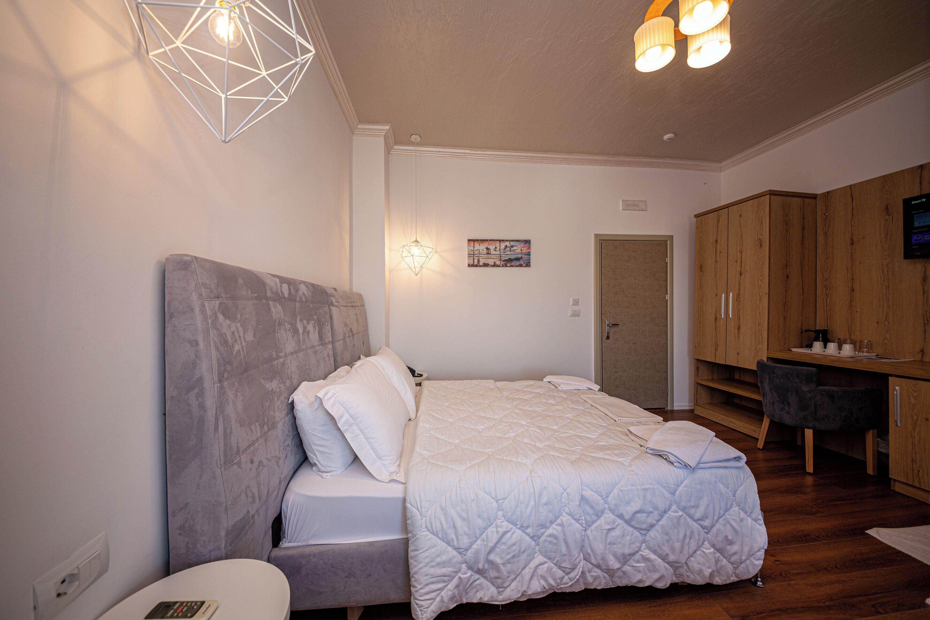 A bedroom with a bed, bedside table, and a desk area with a chair.