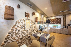 A restaurant with stone walls, wooden barrels, and a tiled floor. - Hotel Murati (Ksamil)