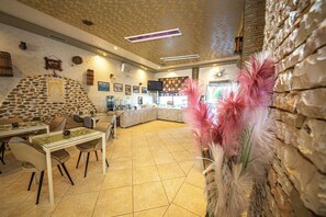 Un restaurante con pared de piedra, una barra y una zona de estar con mesas y sillas.